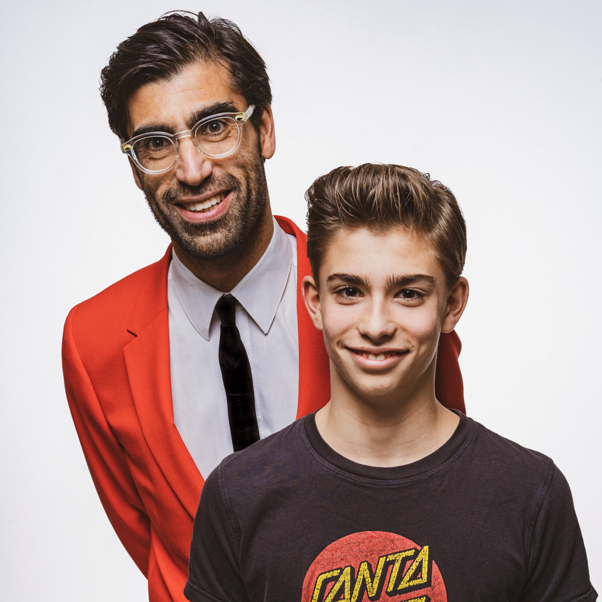 Man in a red blazer and young boy in a black t-shirt with a red logo on a white background