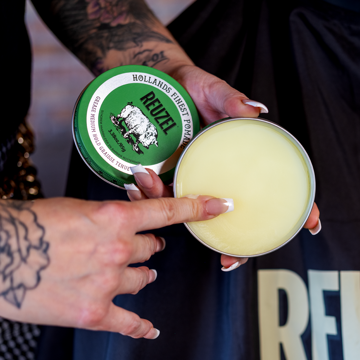 Green Reuzel Pomade grease container with a black lid and label, showcasing the thick, green-colored hair styling pomade.