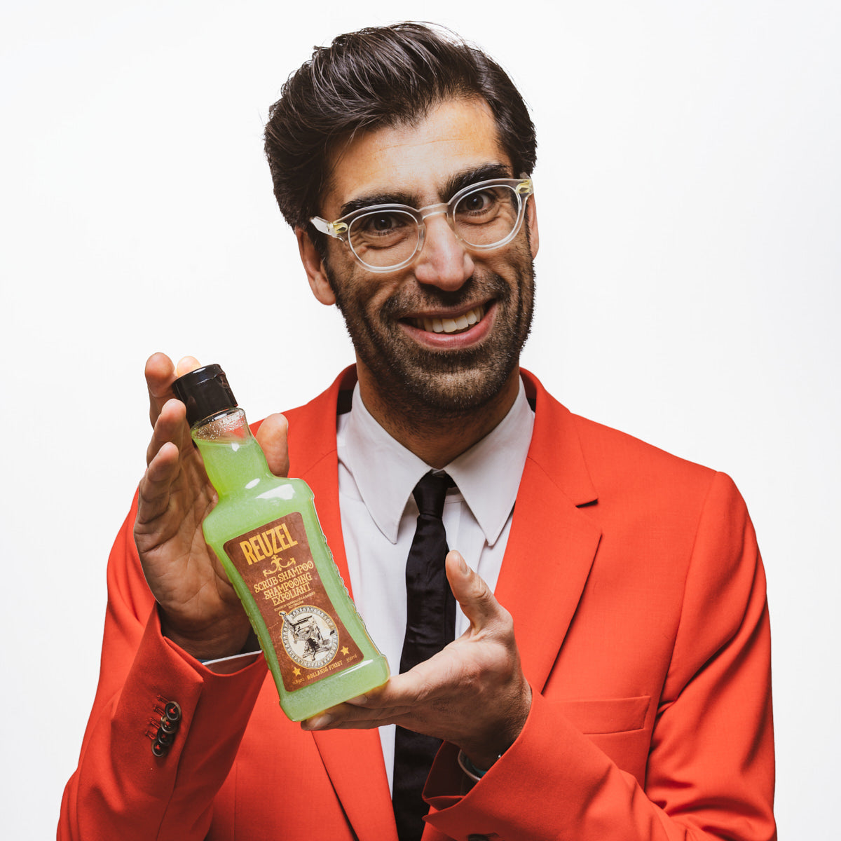Man in a red suit holding a bottle of 'Ruzel' Scrub Shampoo product against a white background